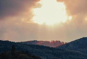 un buco nel cielo - il sole illumina la cima della montagna foto