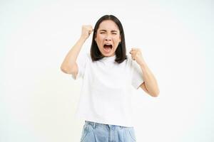 arrabbiato coreano donna, urlando e urlando, guardare male e frustrato, tremante mani, in piedi al di sopra di bianca sfondo foto