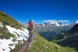 motociclista su sentiero di montagna in un bellissimo paesaggio sulle alpi foto