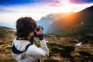 ragazza che fotografa il tramonto in montagna foto