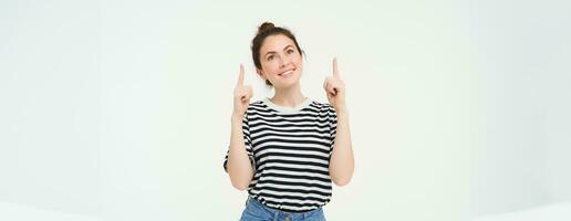 pubblicità e stile di vita concetto. sorridente carino donna puntamento dita su, mostrando annuncio, bandiera su superiore, in piedi al di sopra di bianca sfondo foto