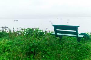 solitario panchina tra il bardane su un' alto riva del mare foto