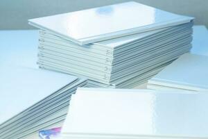pile di appena stampato fotolibri con pulito bianca coperture su il tavolo avvicinamento foto