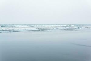 nebbioso paesaggio marino, freddo oceano riva con un' largo spiaggia foto