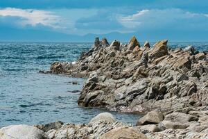 acuto frastagliato basalto rocce su il mare costa foto