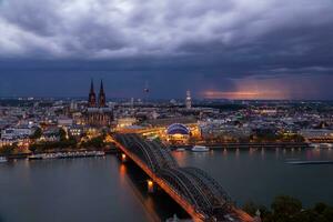 drammatico tempesta nuvole al di sopra di colonia Cattedrale e hohenzollern ponte nel il tramonto foto