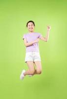 corpo pieno giovane ragazza asiatica che salta, isolato su sfondo verde foto
