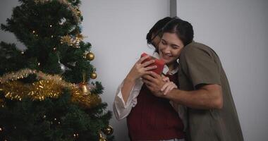 ritratto di giovane uomo siamo Abbracciare una persona loro amiche, Tenere un' bicchiere di vino e godendo in piedi accanto il Natale albero nel il stanza, amanti avere momento romantico e contento insieme foto