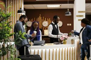 giovane africano americano coppia Riempimento su registrazione modulo mentre controllo nel a Hotel davanti scrivania. turisti in arrivo a ricorrere firma documenti durante registrare procedura, in piedi a ricezione la zona foto