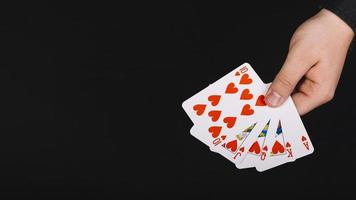 La mano del giocatore di poker scala reale cuore sfondo nero foto