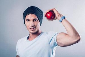 l'aspetto sportivo del giovane mostra i muscoli e tiene le mele nelle sue mani foto