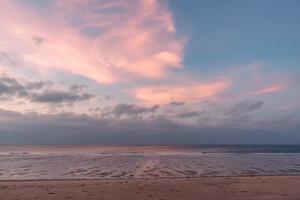 la mattina presto in riva al mare, il cielo e la spiaggia sono leggermente rossi foto