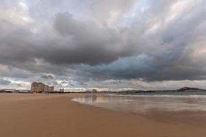 il cielo è coperto di nuvole scure e la spiaggia è nuvolosa foto