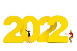 Persone in miniatura adolescente spruzzare vernice numero 2022 su sfondo bianco foto