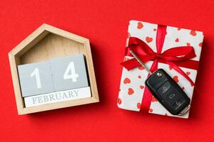superiore Visualizza di auto chiave su un' regalo scatola con rosso cuori e festivo calendario su colorato sfondo. il quattordicesimo di febbraio. presente per San Valentino giorno concetto foto