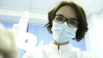 primo persona Visualizza di un' giovane femmina dentista nel maschera approcci con Strumenti. media. giovane medico in piedi al di sopra di il paziente, guardare a telecamera. foto