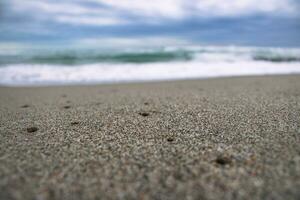 vicino su mare sabbia spiaggia con schiuma e onde foto. sabbia spiaggia superficie con selettivo messa a fuoco. foto