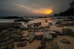 tramonto a il spiaggia con rocce e acqua foto