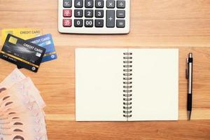 calcolatrice carte di credito e denaro, banconote tailandesi, penne sul tavolo foto
