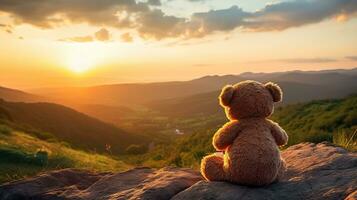 ai generato indietro Visualizza di orsacchiotto orso giocattolo seduta con sfondo di montagna Visualizza a tramonto foto