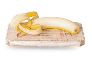 un' pelato Banana bugie su un' di legno tavola isolato su un' bianca sfondo. tropicale frutta, salutare cibo. foto