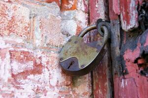 un vecchio lucchetto su chiuso porte, un' arrugginito serratura su il cancello. foto