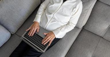 calma donna anziana che naviga nel computer portatile in soggiorno foto