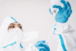 medico in costume che lavora con il contagocce durante la pandemia