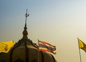 tailandese bandiera e il bandiera di il re nel davanti di il moschea edificio con sera cielo foto