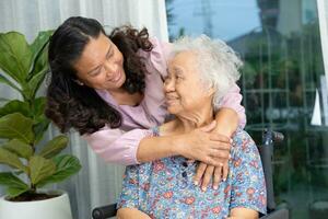 badante Aiuto asiatico anziano donna su sedia a rotelle con amore a casa. foto
