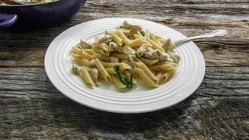 penne con pollo, aglio e brocolii su tavola in legno rustico foto