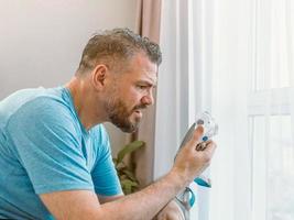 infelice uomo scioccato con problemi respiratori cronici sorpreso dall'uso della macchina cpap seduto sul letto in camera da letto. assistenza sanitaria, cpap, terapia dell'apnea ostruttiva del sonno, concetto di russamento foto