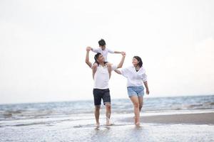 genitori attivi e persone attività all'aperto durante le vacanze estive e le vacanze con i bambini. La famiglia felice e il figlio camminano con il divertimento del mare al tramonto sulla spiaggia di sabbia. foto