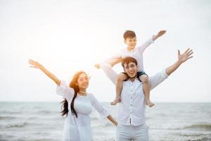 genitori attivi e persone attività all'aperto durante le vacanze estive e le vacanze con i bambini. La famiglia felice e il figlio camminano con il divertimento del mare al tramonto sulla spiaggia di sabbia. foto