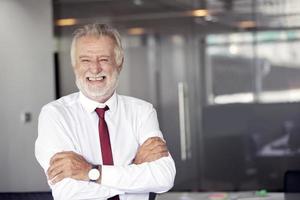 felice bel vecchio uomo d'affari in piedi e sorridente in ufficio foto