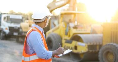 ingegnere asiatico con elmetto protettivo che utilizza computer tablet pc ispezione e lavoro in cantiere foto