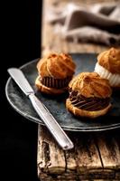 Deliziosi profiteroles su tavola in legno rustico foto