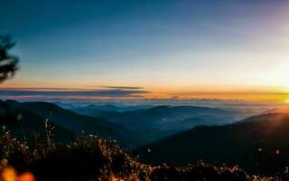 ai generato crepuscolo abbraccio un' sinfonia di colori al di sopra di maestoso montagna picchi ai generato foto