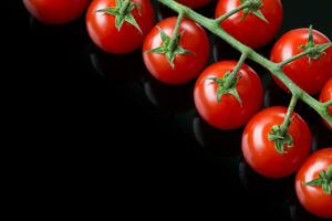 fresco ciliegia pomodori su un' nero sfondo. mazzo di fresco ciliegia pomodoro su un' nero sfondo foto