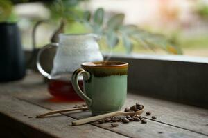 nero caffè tazza e bicchiere vaso ricarica posto come un' impostato su il di legno tavolo su il balcone di il Casa. decorare con caffè fagioli mettere nel un' di legno cucchiaio. per migliorare il gusto di potabile. foto