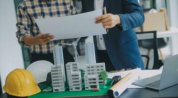 costruzione e struttura concetto di ingegnere o architetto incontro per progetto Lavorando con compagno e ingegneria utensili su modello edificio e planimetria nel Lavorando luogo, contrarre per tutti e due aziende. foto