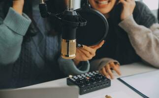 donna registrazione un' Podcast su sua il computer portatile computer con cuffie e un' microscopio. femmina podcaster fabbricazione Audio Podcast a partire dal sua casa studio. foto