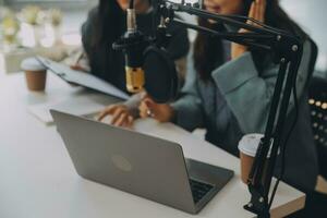 donna registrazione un' Podcast su sua il computer portatile computer con cuffie e un' microscopio. femmina podcaster fabbricazione Audio Podcast a partire dal sua casa studio. foto