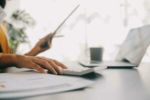 il ritratto di una giovane donna asiatica libera professionista sta lavorando sul tablet del computer in un ufficio moderno. fare un rapporto di analisi contabile dati di investimento immobiliare, concetto di sistemi finanziari e fiscali. foto