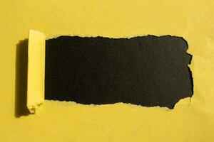 giallo strappato carta buco su un' nero sfondo con copia spazio per il tuo testo foto