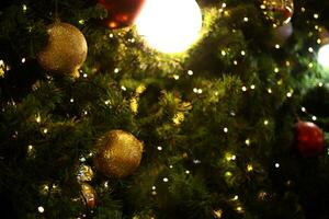 vicino su decorazione palla e leggero lampadina su Natale albero a notte foto