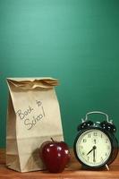pranzo scolastico, mela e orologio sulla scrivania a scuola foto