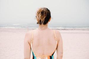 schiena di una giovane donna in costume da bagno, spiaggia malinconica, vacanza, sensazione dopo l'estate