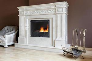 camino in marmo bianco in stile classico con legna ardente all'interno. foto