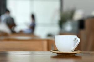 tazza di caffè bianco sul pavimento di legno nella caffetteria.